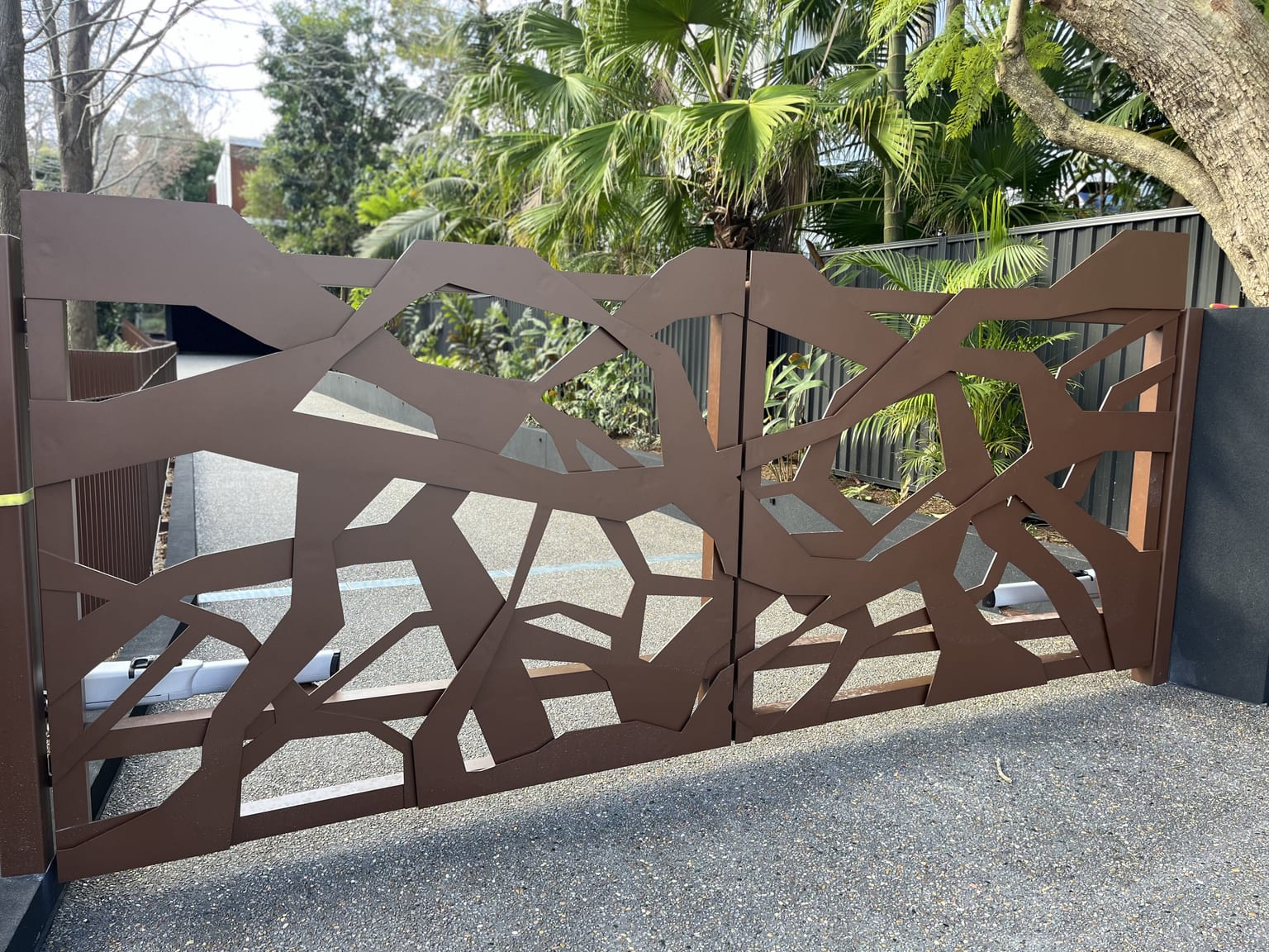 Decorative laser-cut metal driveway gate with organic branch pattern on a Sydney home